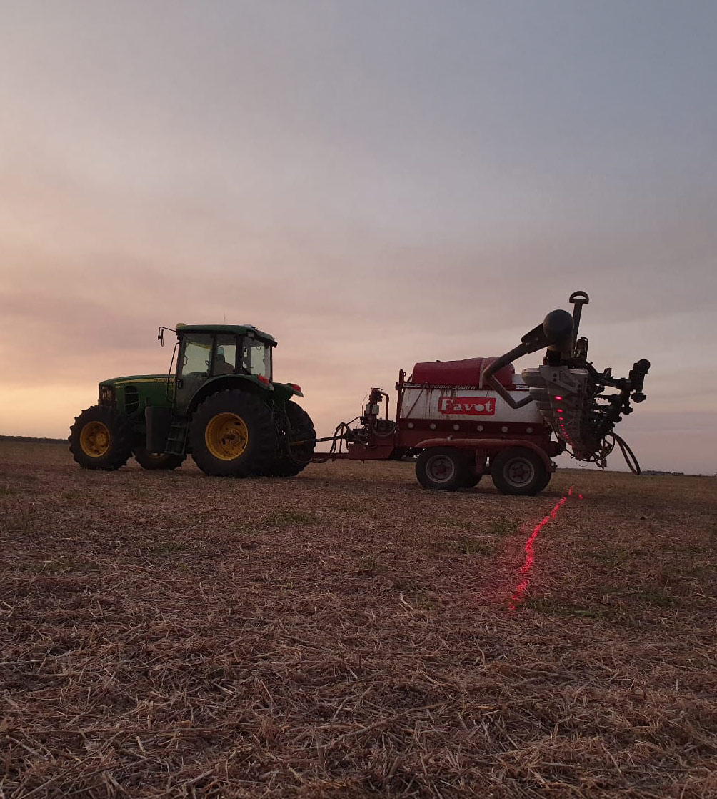 Tractor con pulverizador de Initio AG en un lote al atardecer